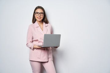 Confident business woman wearing pink suit holding opened laptop