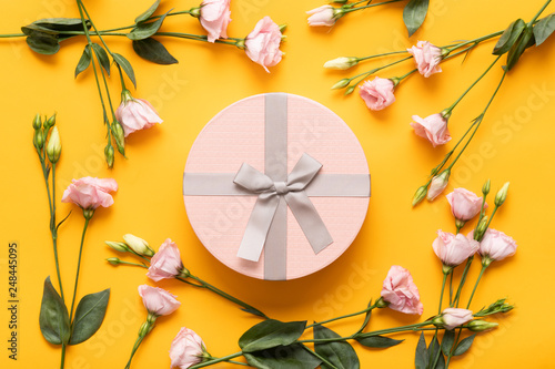 Happy Mother's Day, Women's Day, Valentine's Day or Birthday Yellow and Pastel Pink Colored Background. Flat lay greeting card with beautiful gift box and pink lisianthus flowers.
