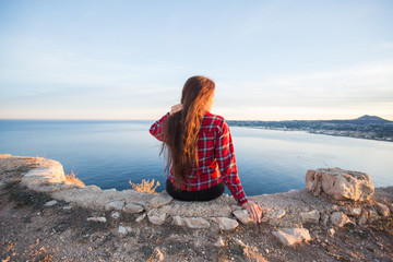 Travel, adventures and nature concept - Female tourists sitting alone on the mountain