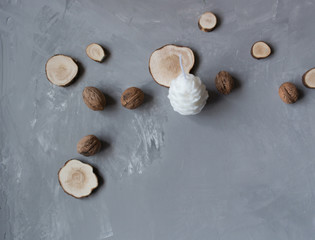 white candle in the shape of a cone surrounded by wood and walnuts