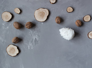 white candle in the shape of a cone surrounded by wood and walnuts