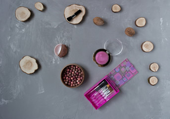  A set of pink makeup brushes with blush on a gray phon