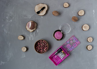  A set of pink makeup brushes with blush on a gray phon