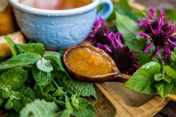 tea on a tray on a table above the berries ššta mint echinacea camomile jam apricot spoon wooden...
