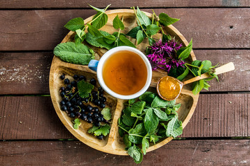 tea on a tray on a table above the berries ššta mint echinacea camomile jam apricot spoon wooden...