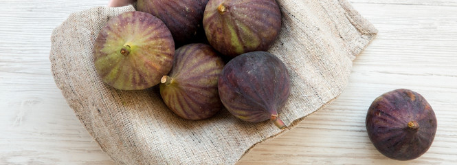 Fresh figs in a pink bowl on a white wooden background, top view. Flat lay, overhead, from above.