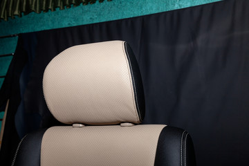 Headrest of front seat with combined leather trim in two colors of black and beige, located on the...