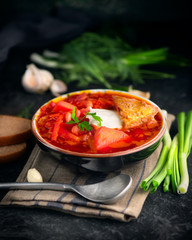 Traditional Ukrainian russian borscht. Plate of red beet root soup borsch on black rustic table. Beetroot soup. Traditional Ukrainian cuisine. Vertical shot