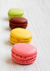 Sweet and colorful macarons on a white wooden background, side view. Close-up.