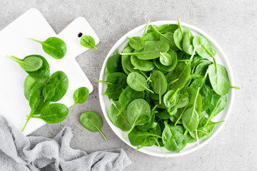Fresh spinach leaves on white plate. Healthy vegan food. Top view