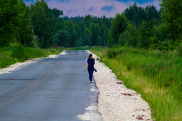 woman walking on country road in forest