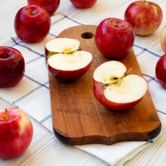 Fresh raw red apples on rustic board on a white wooden background, side view. Close-up.