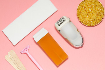 Beauty, depilation and hair removal concept - wax, spatula, epilator and safety razor on pink background. Top view.