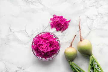 Pile of fresh organic shredded pink watermelon radish on marble table. Top view. 