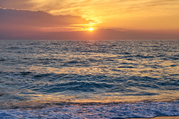 Tropical beach. Colorful sunset seascape. Waves with foam hitting sand.