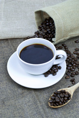 cup of coffee with beans on wooden table