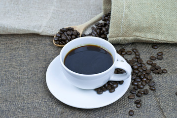 cup of coffee with beans on wooden table