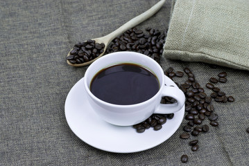 cup of coffee with beans on wooden table