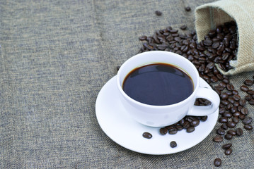 cup of coffee with beans on wooden table