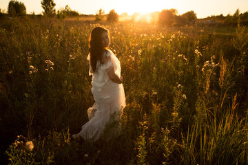 Girl in a dress walks in the evening at sunset