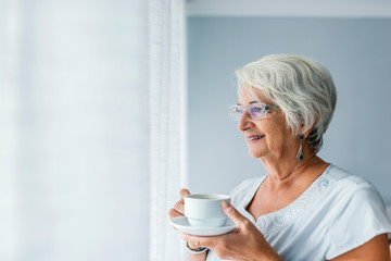 Senior woman at the window holding a cup of tea
