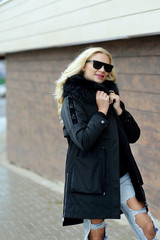 girl in black down jacket and black glasses posing on the street