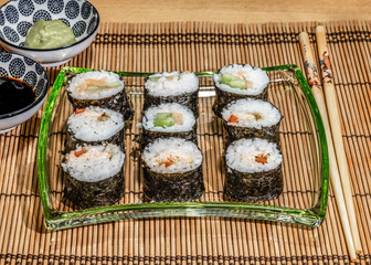 Sushi is a dish made from steamed white rice, rolled in gim with salmon and other ingredients with caviar and served in bite-size slices. Wasabi and soy sauces in saucers.