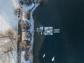 Aerial view of sail boats anchored in front of shore during winter time.