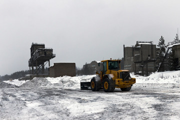 tractor cleans snow in the parking lot of industrial vehicles at the plant