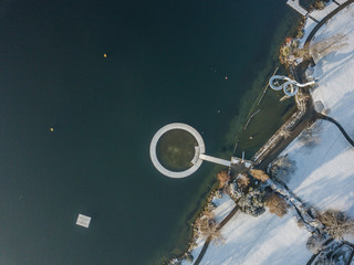 Aerial view of water slide on lake shore in winter time. Snow covered surface of leisure park in Switzerland.