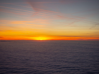 Aerial view from the airplane to a massive sea of clouds at the sunset