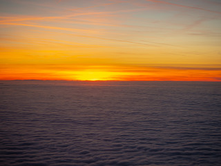Aerial view from the airplane to a massive sea of clouds at the sunset