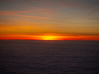 Aerial view from the airplane to a massive sea of clouds at the sunset