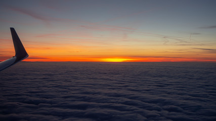 Aerial view from the airplane to a massive sea of clouds at the sunset
