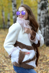 girl in a coat and sunglasses walking in the woods