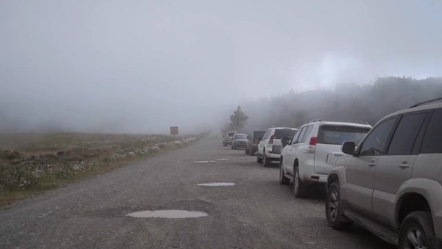 Slow Motion: Cars Parked on Gravel Road in Misty Landscape