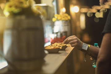 young guy tasting cheesy jalapeno skillet potatoes fries with cheddar and jalapenos from the food truck table at the street food festival in the night light