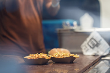 cheesy jalapeno skillet potatoes fries with cheddar and jalapenos on the food truck table at the street food festival at night ready to be served