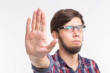 People, expression and gesture concept - young man showing stop gesture on white background