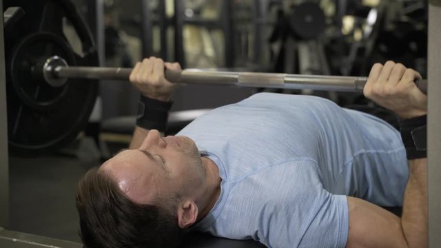 Close up image of man doing bench press at the gym.