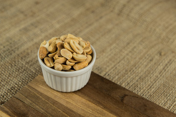 peanuts in white bowl on wooden table