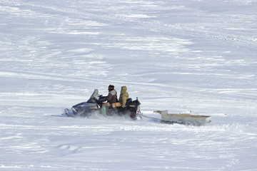 Fishermen snowmobile ride on the frozen river.