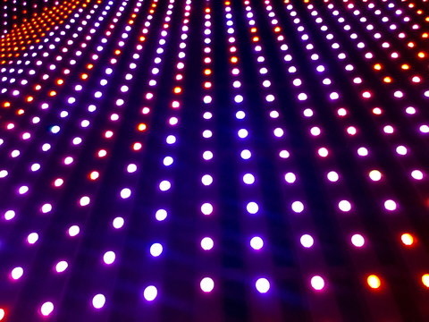 Abstract Led wall with soft focus. Rows neon light bulbs on dark background. Shades of blue, red and purple glow