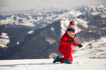 Fototapeta na wymiar Portrait of happy little girl playing on the top of mount with ice and snow
