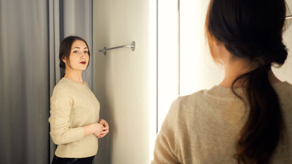 Beautiful woman measures the clothes in a fitting room.