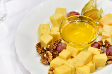 a lot of types of cheese (Parmesan, Gouda, Emmental cheese) with honey, walnuts and physalis. appetizer in a French restaurant, snack for wine. dish for banquet, menu for wedding