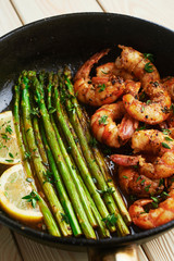fried langoustines with asparagus decorated with lemon slices. roasted king prawns tiger shrimps with green garnish