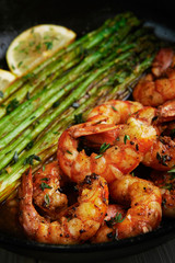 fried langoustines with asparagus decorated with lemon slices. roasted king prawns tiger shrimps with green garnish