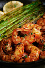 fried langoustines with asparagus decorated with lemon slices. roasted king prawns tiger shrimps with green garnish