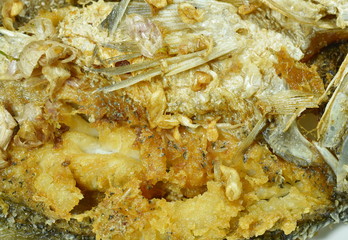 close up of deep fried salty bass fish with garlic on plate